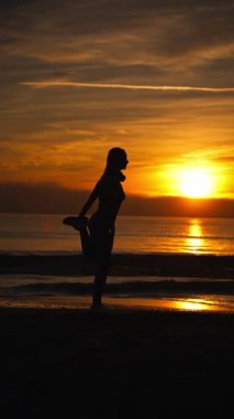 Gün batımında sahilde genç bir adamın silueti.