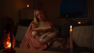 Kadın geceleri oturma odasında yerde kitap okuyor..