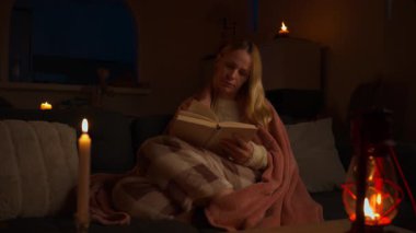 Evde kitap okuyan genç bir kadın.