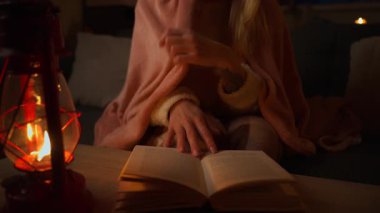 Kız karanlık bir odada kitap okuyor.