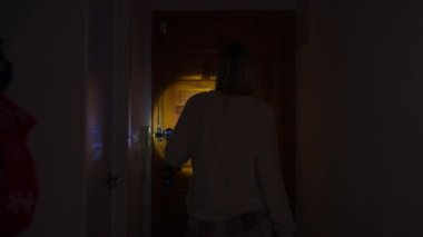 Genç bir kadın evinin kapısını açıyor.