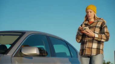 Kadın tamirci garajda araba motorunu kontrol ediyor.