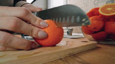 Kadın taze portakalları paslanmaz çelik bir lavaboda yıkayarak hazırlıyor. Bir portakalı akan suyun altında tutarken, bir kaç tanesi de lavaboya ve yakınlardaki bir kaseye yerleştiriliyor.