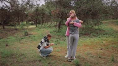 Üç çocuk açık havada bir anda birbirlerine bağlanırlar, bir çocuk diğerine sarılırken üçüncü bir çocuk yerde çömelir, hepsi ağaçların ve yemyeşil çimenlerin üzerine kurulur.