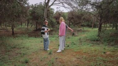 Ormandaki bir grup çocuk, bir çocuk diğerini kucaklarken, diğer bir çocuk da ağaçlarla çevrili ve açık havada yemyeşil bir ortamda dikiliyor.