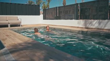 happy couple of young woman with long hair and black swimsuit in a swimming pool
