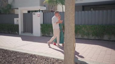 Genç bir adam ve bir kadın kumsalda yürüyor, gülümsüyor ve gülüyorlar. Mutlu adam ve kız sokakta yürüyorlar..