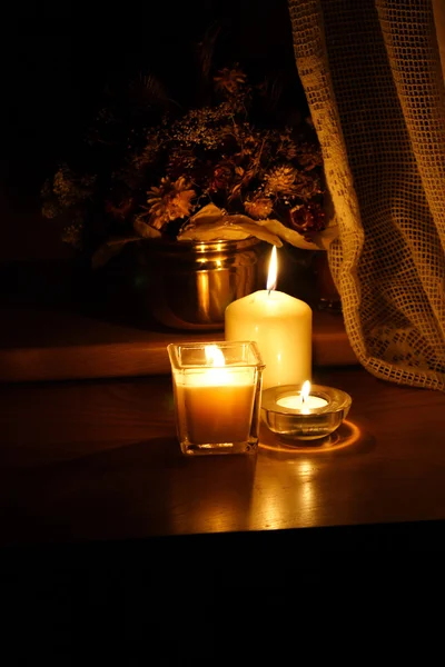 Luzes de vela com um monte de flores no interior escuro — Fotografia de Stock