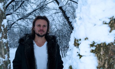 Kış ormanındaki sakallı bir adamın portresini bir ağaçtan seyret.