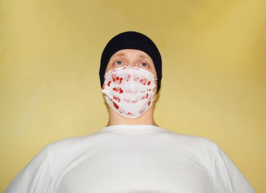 Şapkalı bir adam ve kırmızı benekli bir tıbbi maske.