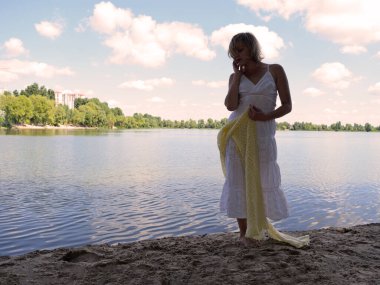 A young woman in a white dress near the lak