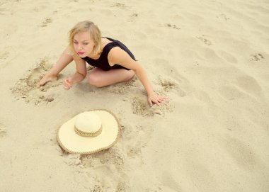 A young woman in a bathing suit on the sand near a ha