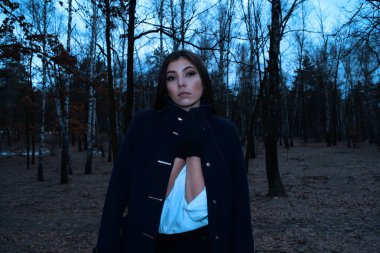 Çam ağacının arka planında mavi ceketli esmer bir kadın.