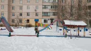 Kışın şehirde çok katlı bir evin yanındaki oyun parkının görüntüsü