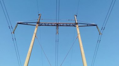 Mavi gökyüzüne karşı yüksek voltaj direklerinin alt görüntüsü. Elektrik, teknoloji.