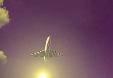 Gökyüzünün arka planında sarı güneşli yolcu uçağı