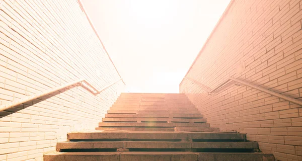 Şehirdeki yeraltı geçidinden merdivenlerin alt görüntüsü. Güneş ışıldıyor.