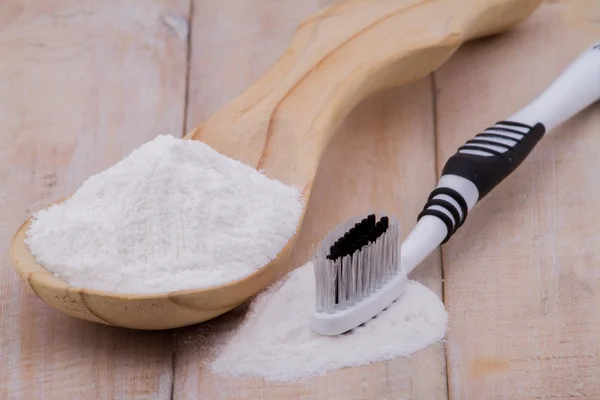 Bicarbonato de sodio y cepillo sobre mesa de madera — Foto de Stock