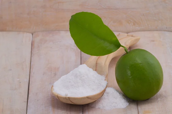 Membakar soda dalam sendok dan buah lemon di atas meja kayu — Stok Foto