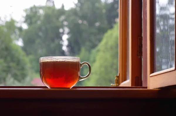 An open window and a mug of tea on the windowsill