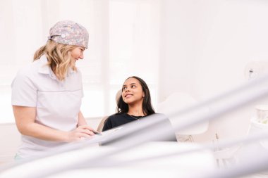 Kadın Diş Hekimi, Gülümseyen Genç Kadın Hasta Diş Hekimliğinde Ağız Tedavisini Açıklıyor