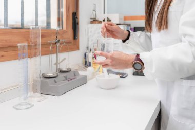 Kadın eczacının eczane laboratuarında cam çubukla ilaç hazırladığını gördüm.