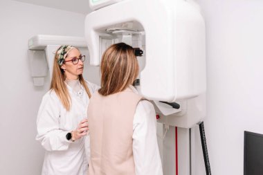 Kadın dişçi, dişçi muayenehanesinde diş röntgeni için hasta yerleştirdi.