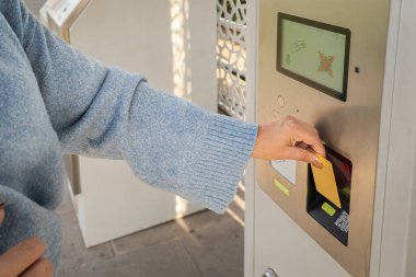 Bilet almak için bir ödeme makinesine kart sokan kadının elini kapat.