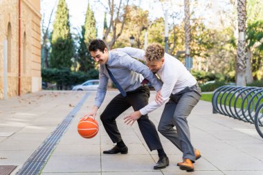 Dışarıda basketbol oynayan iki neşeli iş adamı, iş hayatı dengesinin keyfini çıkarıyorlar.