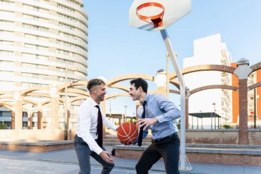 Dışarıda basketbol oynarken resmi giyinmiş iki meslektaş.
