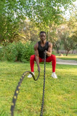 Afrika kökenli Amerikalı sporcu. Parkta savaş halatlarıyla egzersiz yapıyor. Sağlıklı yaşam tarzı ve formda.