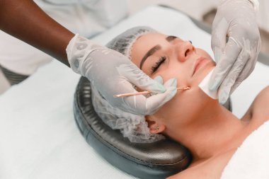 Estetisyen eller cilt tedavisi sırasında kadınların yüz gözeneklerini temizlemek için alet sökücü kullanıyor