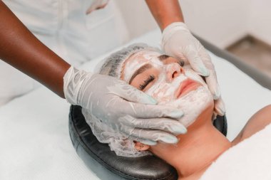 Güzellik uzmanı spa 'da cilt bakımı sırasında rahatlatıcı yüz maskesi takıyor.