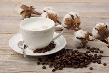 Bir bardak süt kahve, kahve çekirdekleri ve pamuk çiçek ile