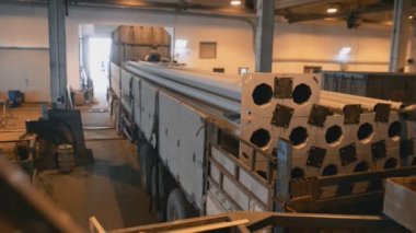 uzun direkleri ışık direkleri üzerinde bir büyük fabrika dükkan üretiminde flatbed kamyon ağır el ile yükleme