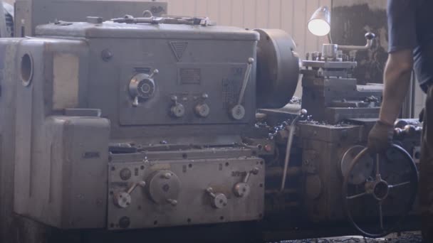 l'opérateur est debout à la fraiseuse et aux commandes de tour et de main et la profondeur de coupe de la couche de pièce de copeaux de métal. Travail longitudinal machine usine production 