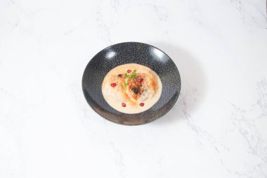 Dahi Baray or bhalla Yogurt Lentil Fritters Garnished with Pomegranate and Spices in bowl isolated on marble background side view