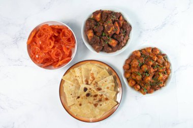 South Asian Iftar Feast Full Dinner Spread with Paratha, Jalebi, Dum Aloo, and Aloo Gosht isolated on marble background top view