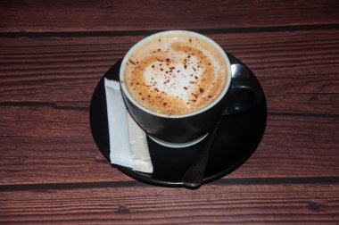 Creamy White Chocolate Mocha Latte in Ceramic Mug with sugar packet on wooden table top view of Cozy Cafe Hot milk tea Beverage