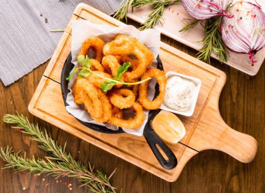 Lezzetli soslu altın çıtır kalamar halkaları bir restoranda paylaşmak için mükemmel ya da evde lezzetli bir aperatif olarak yemek için.