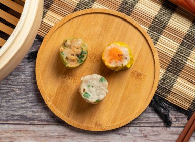 Otantik Çin yemeği Siu Mai dim sum hamur tatlısı buharlı tencereden taze, ahşap bir tabakta nefis ve görsel olarak çekici bir yemek için servis edilir.