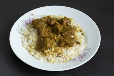 Tüylü beyaz pilavın üzerinde bol bol servis edilen baharatlı körili biftek, rahatlatıcı ve lezzetli bir yemek.