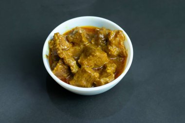 Lezzetli körili biftek, beyaz kasede servis ediliyor. Pürüzsüz, koyu bir arka planı var. Yemek blogları için mükemmel.