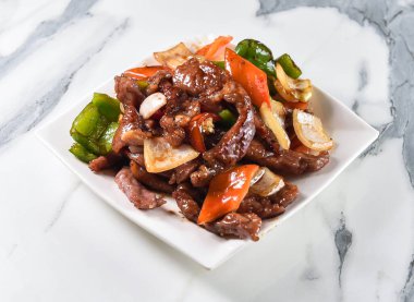 Cızırdayan baharatlı biftek kızartması, canlı biber ve soğanla en sevdiğiniz restoranda hızlı ve lezzetli bir yemeğe hazır.