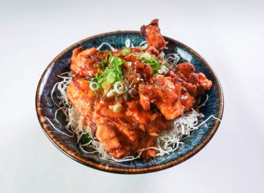 Lezzetli çıtır tavuklu Asya mutfağı, pilav eriştesi ve taze soğan güzel bir kasede servis edilmeye hazır.