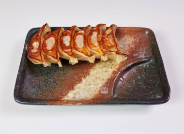 Kızarmış tavada kızartılmış gyoza hamur köfteleri kırsal tabakta, Asyalı yemek tutkunları ve mutfak yaratıcıları için lezzetli bir lezzet.