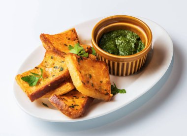 Canlı yeşil pesto soslu altın sarımsaklı ekmek lezzetli ve görsel olarak çekici bir aperatif ya da meze hazırlar.