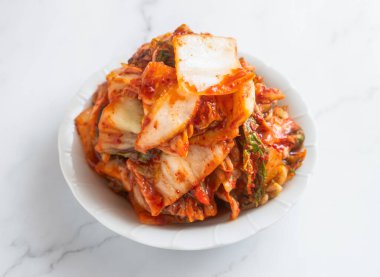 Beyaz tabakta yenmeye hazır Çin lahanalı kimçi. Her yemeğe tat katan lezzetli ve sağlıklı bir Kore mezesi.