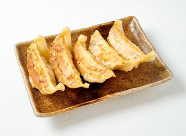 Kırsal bir tabakta servis edilen altın kahverengi gyoza köfteleri tat alma duyuları, Asya mutfağı menüleri ve yemek blogları için mükemmel.