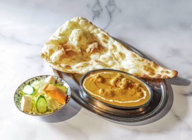 Lezzetli Hint usulü tereyağlı tavuk körili taze ekmek ve salata evde lezzetli ve tatmin edici bir yemek deneyimi için.